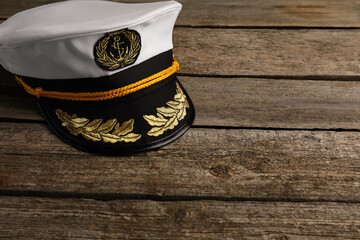 Peaked cap with accessories on wooden background, space for text
