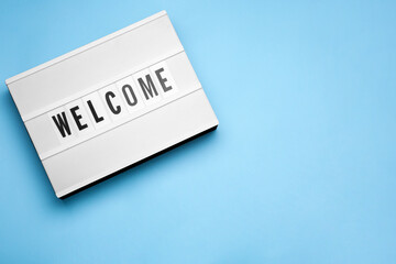 Lightbox with word Welcome on light blue background, top view. Space for text