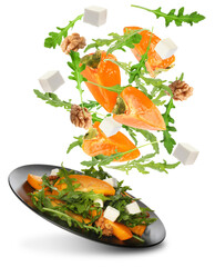 Tasty ingredients for persimmon salad falling into plate on white background
