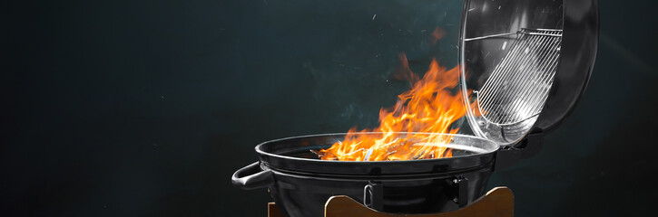 New modern barbecue grill with burning firewood on dark background. Banner design - obrazy, fototapety, plakaty