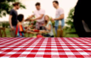 Table with checkered picnic cloth outdoors on sunny day. Space for design