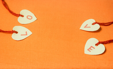 Orange background with paper tied with string written the word love.