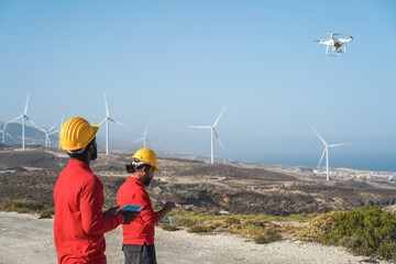 Multiracial engineer men working on windmill farm with digital tablet and drone - Renewable energy concept