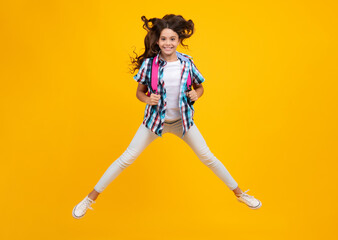Fototapeta na wymiar Schoolgirl in school uniform with school bag. Crazy run and jump. Schoolchild, teen student hold backpack on yellow isolated background.