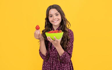 positive teen girl hold strawberry bowl on yellow background