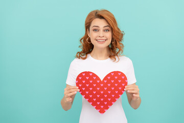smiling redhead woman hold red heart on blue background