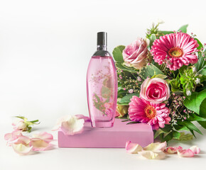 Obraz na płótnie Canvas Pink perfume glass spray bottle on podium with beautiful flower bouquet at white background. Front view