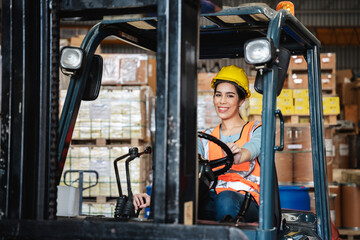 Portrait of a woman working with a forklift in a warehouse with her looking at the camera.