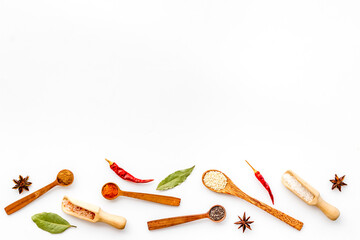 Variety of colorful spices and herbs in wooden spoons on kitchen table, top view