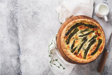Quiche. Homemade asparagus pie or quiche with cheese, pecorino, bacon and spinach on gray concrete light table background. Asparagus and cheese tart.  French Quiche. Top view.