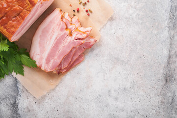 Whole Smoked Slab Bacon. Brisket. Sliced smoked gammon on a wooden table with rosemary, parsley,...