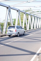 car on the road or iron bridge or jembatan konstruksi besi di kali Luk Ulo, Kebumen, Jawa Tengah, Indonesia - obrazy, fototapety, plakaty