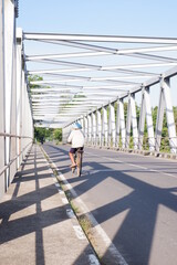 person walking on the bridge or iron bridge or jembatan konstruksi besi di kali Luk Ulo, Kebumen, Jawa Tengah, Indonesia - obrazy, fototapety, plakaty