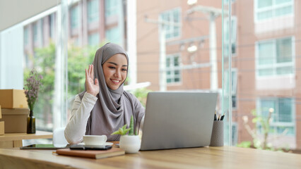 Young smiling beautiful muslim woman using laptop computer working and video conference meeting at home. work from home concept