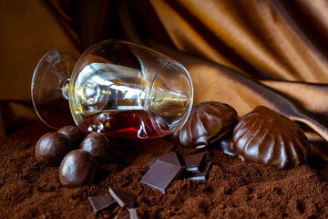 Chocolate candies, marshmallows in chocolate, chocolate bars, ice skate in a lying glass, located on ground coffee on a brown background