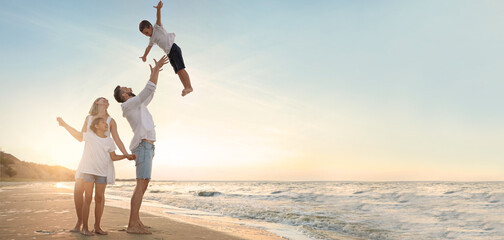 Happy family having fun on sandy beach near sea at sunset, space for text. Banner design