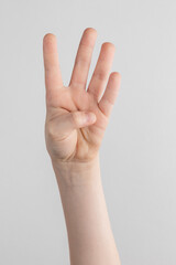 child hand counting and showing four fingers against white and gray background