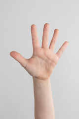 child hand counting and showing five fingers against white and gray background