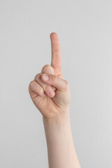 child hand shows the forefinger up against white and gray background