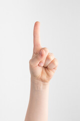 child hand shows the forefinger up against white and gray background