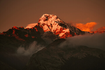 Warm pink and orange dramatic sunrise light over Annapurna mountain range with beautiful clouds, view from Poon hill in Himalayas, Nepal