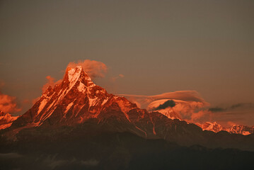 Warm pink and orange dramatic sunrise light over Annapurna mountain range with beautiful clouds, view from Poon hill in Himalayas, Nepal