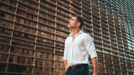 Mature businessman with neat beard wearing white shirt on his way to the office in the financial...
