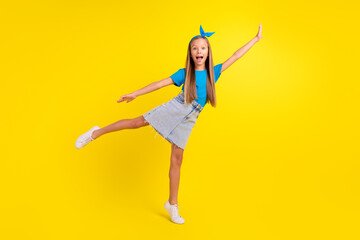Fototapeta na wymiar Full length photo of positive excited pupil stand one leg tip toe raise arm empty space isolated on yellow color background