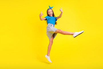 Fototapeta na wymiar Full size photo of active energetic girl jumping hand fingers demonstrate thumb up isolated on yellow color background