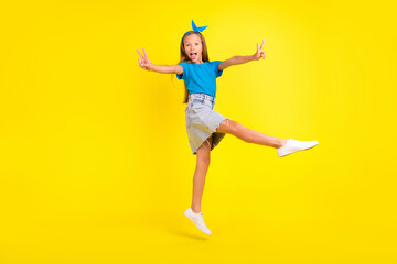Fototapeta na wymiar Full length portrait of excited friendly pupil jump hands fingers demonstrate v-sign isolated on yellow color background