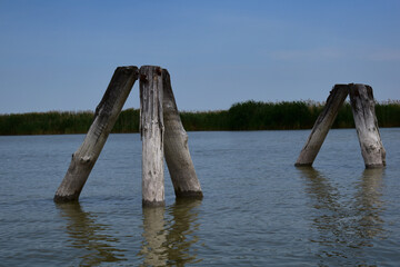 Fototapeta premium See mit Holzpollern mit weitem Horizont im Sommer zur Tourismus Zeit
