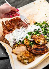 woman hand holding plastic fork with meat and sause outdoor