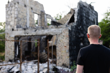 Fototapeta na wymiar Man looking to his ruined and burnt house by russian troops.