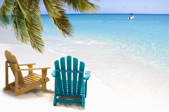 Beach chairs  and soft wave of turquoise ocean water under palm branch
