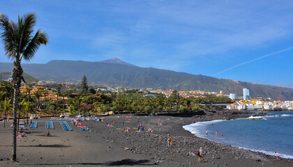 Fototapeta na wymiar Playa Jardin with black volcanic sand. In the distance, the volcano Teide. Puerto de la Cruz, Tenerife, Spain.