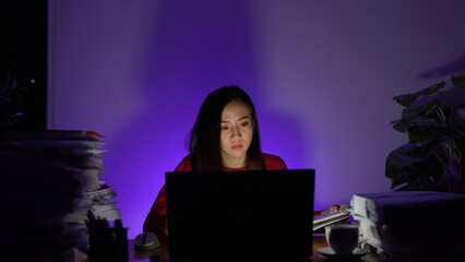 Stressed young asian woman sitting work overtime doing late time business at office in night on desk, Exhausted businesswoman concept.