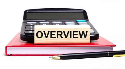 A burgundy notebook on a white background. On it is a black calculator, a pen and a wooden block with a OVERVIEW text. Business concept