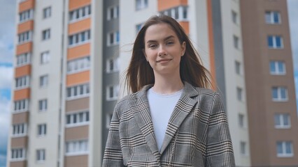 Portrait of a girl in front of a high-rise apartment building.