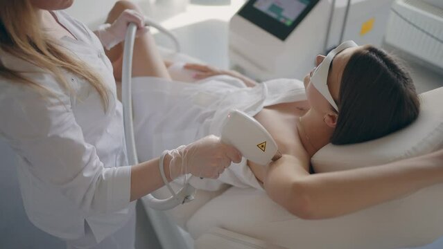 laser hair removal of armpit in modern cosmetology clinic, adult woman is doing epilation in beauty salon
