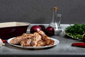 Raw chicken wings with spices on a white plate on the kitchen table. Preparing for barbecuing.