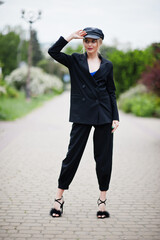 Portrait of beautiful blonde sexy fashion woman model in cap and in all black with bright makeup.