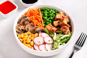 Vegan buddha bowl with tofu, colorful vegetables on base of brown rice.