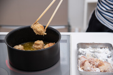 IHで唐揚げを揚げている女性の手元