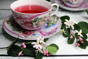 A cup of tea on a wooden table with a background of white and pink flowers