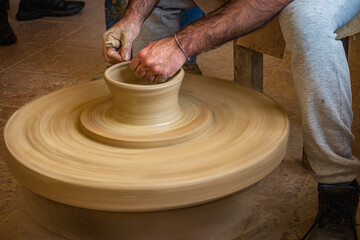 Potter shaping a piece of clay on a low wheel in Amarante, Portugal.