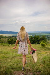 beautiful girl in the summer dress in the green meadow, the view from the back.