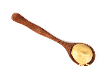 High angle view of wooden spoon with Dijon mustard isolated on white background.