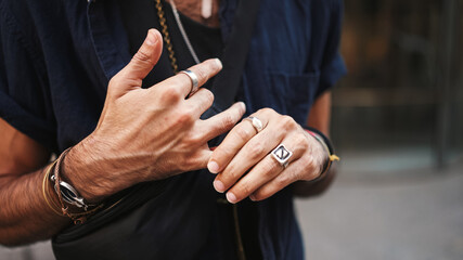 Close-up of male hands in bracelets and rings. Man adjusts the ring on his finger. Guy twists the ring on his finger - obrazy, fototapety, plakaty