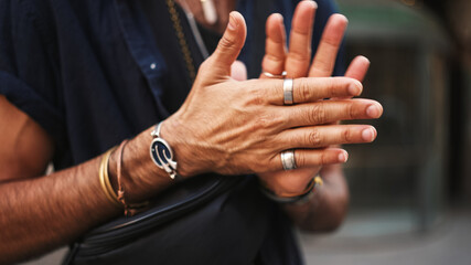 Close-up of male hands in bracelets and rings. Man adjusts the ring on his finger. Guy twists the ring on his finger - obrazy, fototapety, plakaty