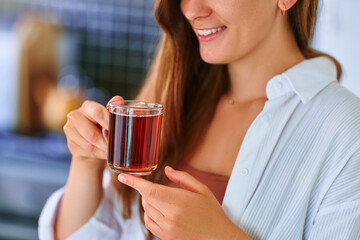 Happy beautiful joyful carefree satisfied attractive woman drinking hot black tea at home kitchen